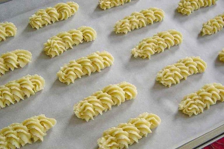 Zutaten 120 g Zucker 1 Ei 220 g Marzipan 250 g Butter 4 Tropfen Bittermandelaroma 120 g Speisestärke 250 g Mehl 1 TL Backpulver Zubereitung 1. Als erstes die Butter, Zucker schaumig in einer Schüssel rühren. Danach das Marzipan zerkleinern und dazu geben. Gut unterrühren, danach das Ei ebenfalls unterrühren. Mehl, Speisestärke, Aroma und Backpulver dazu geben und alles zu einem glatten Teig verarbeiten. 2. Als nachstes Zwei Backbleche mit Backpapier auslegen. Den Teig mittels Spritzbeutel und mittlerer Sterntülle auf die Bleche spritzen. Der Teig reicht je nach Größe für ca. 60 Plätzchen. 3. Nun Im vorgeheizten Backofen bei 190°C Umluft ca. 10 Minuten backen. Probieren sie auch: KARTOFFEL-HACKFLEISCH-TOPF MIT SCHMAND UND MÖHREN Die Plätzchen sollen nur leicht Farbe bekommen. Sie sind direkt nach dem backen noch weich, werden nach dem Auskühlen fest bzw. schön mürbe.