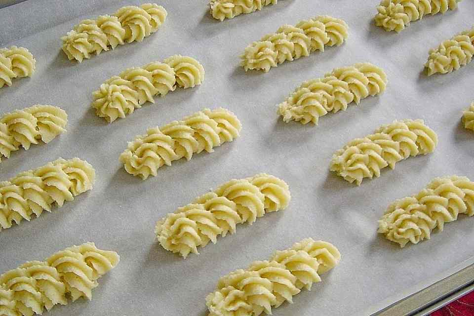 Zutaten 120 g Zucker 1 Ei 220 g Marzipan 250 g Butter 4 Tropfen Bittermandelaroma 120 g Speisestärke 250 g Mehl 1 TL Backpulver Zubereitung 1. Als erstes die Butter, Zucker schaumig in einer Schüssel rühren. Danach das Marzipan zerkleinern und dazu geben. Gut unterrühren, danach das Ei ebenfalls unterrühren. Mehl, Speisestärke, Aroma und Backpulver dazu geben und alles zu einem glatten Teig verarbeiten. 2. Als nachstes Zwei Backbleche mit Backpapier auslegen. Den Teig mittels Spritzbeutel und mittlerer Sterntülle auf die Bleche spritzen. Der Teig reicht je nach Größe für ca. 60 Plätzchen. 3. Nun Im vorgeheizten Backofen bei 190°C Umluft ca. 10 Minuten backen. Probieren sie auch: KARTOFFEL-HACKFLEISCH-TOPF MIT SCHMAND UND MÖHREN Die Plätzchen sollen nur leicht Farbe bekommen. Sie sind direkt nach dem backen noch weich, werden nach dem Auskühlen fest bzw. schön mürbe.