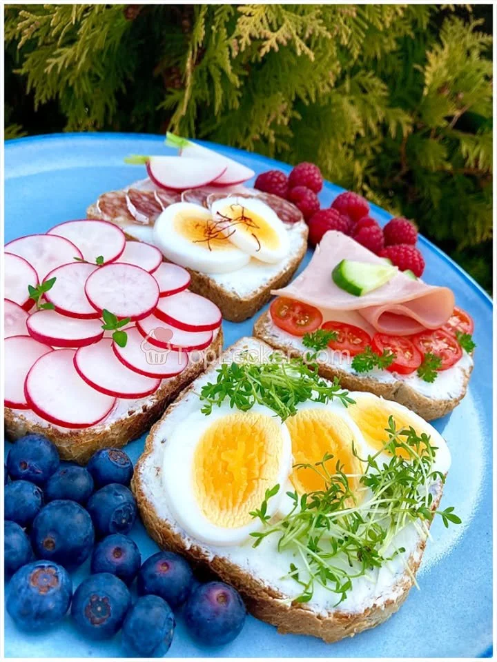 Vollkornbrot mit Frischkäse und buntem Belag auf einem Holzbrett
