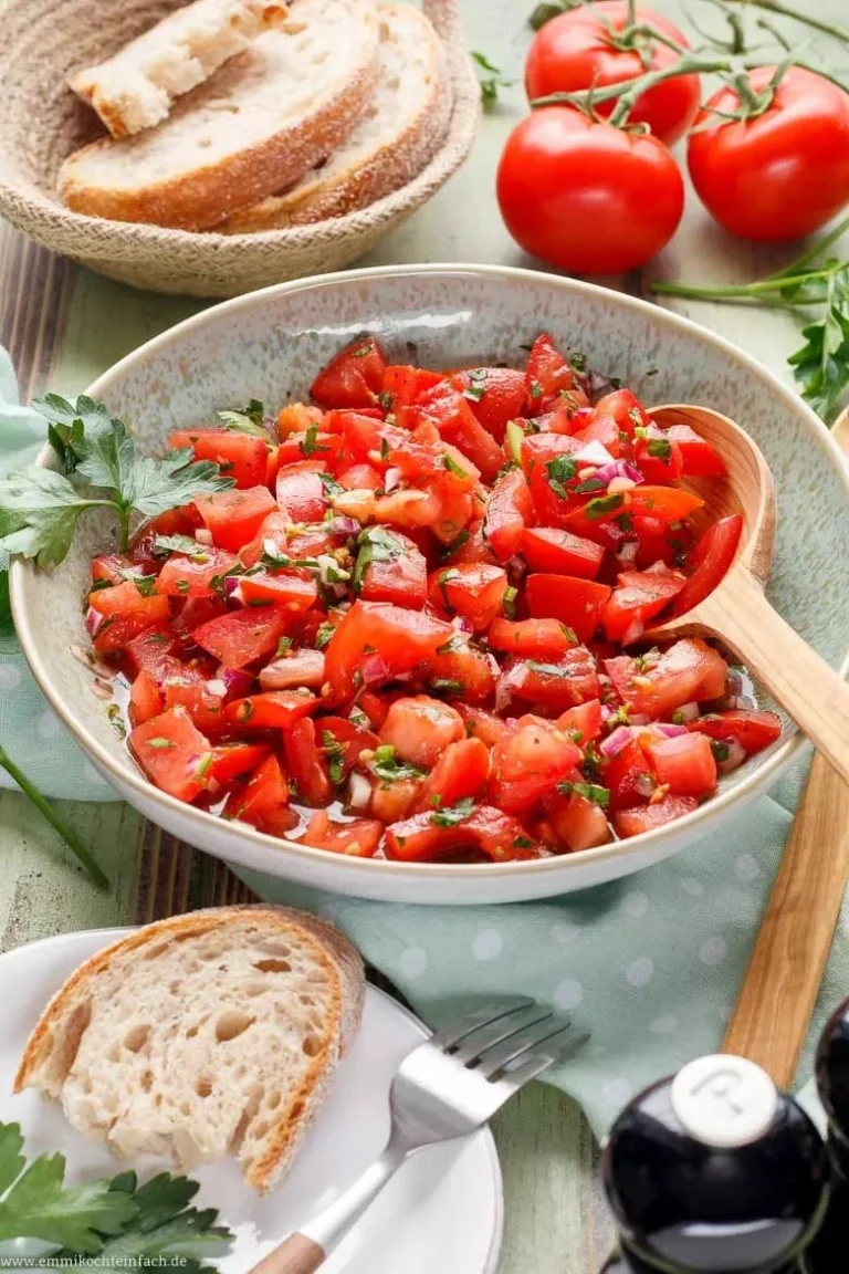 Leckerer Tomatensalat mit Zwiebeln auf einem Teller angerichtet.