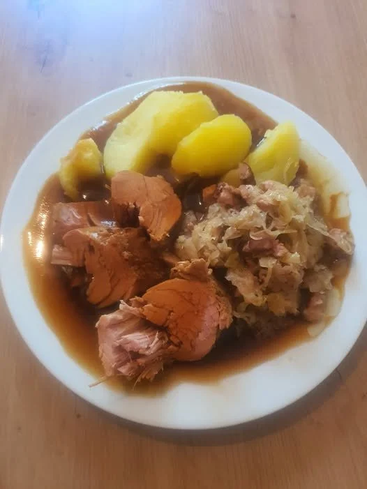 Klassisches Gericht Kaßler mit Sauerkraut und Kartoffeln auf einem Teller.