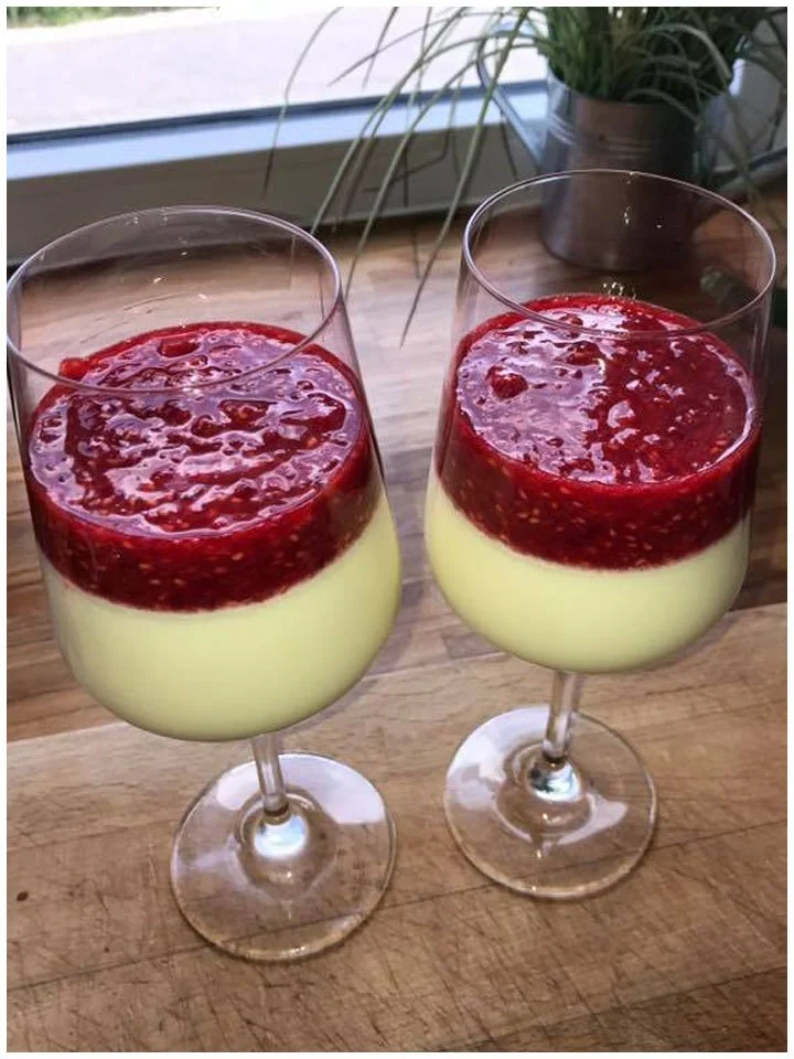 Himbeer-Panna-Cotta auf einem Teller, garniert mit frischen Himbeeren und Minze.