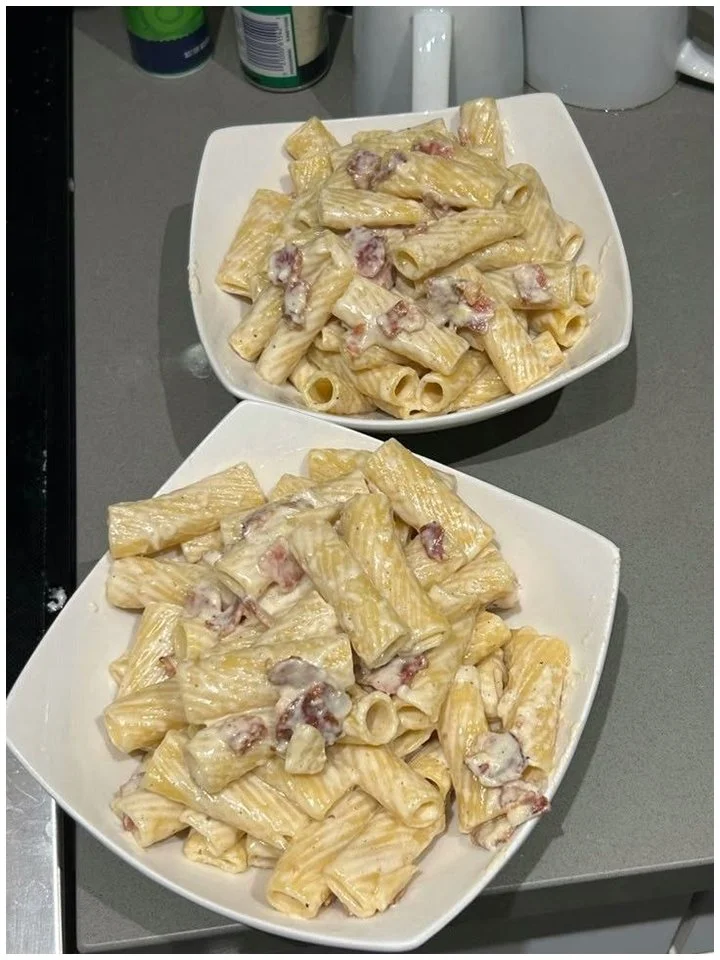 Teller mit Rigatoni Carbonara, mit Käse und Speck garniert