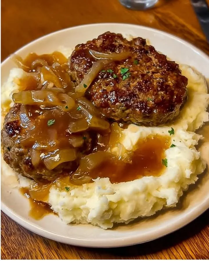 Buletten mit Kartoffelbrei und Zwiebelsoße auf einem Teller serviert.
