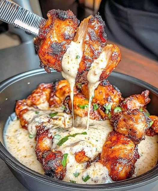 Gegrillte Hähnchenstücke serviert mit cremiger Knoblauchsoße auf einem Teller.