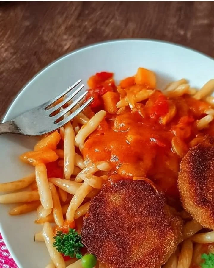 Nudeln mit Tomatensauce und knusprigem Jägerschnitzel auf einem Teller serviert.