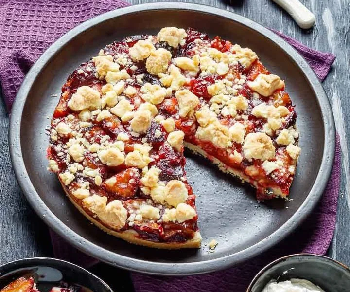 Schnitt von Zwetschgenkuchen mit Streuseln auf einem Teller