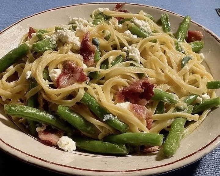 Bandnudeln mit grünen Bohnen, Bacon und Schafskäse auf einem Teller serviert
